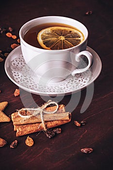 Vertical image of white cup of tea with lemon and cinnamon