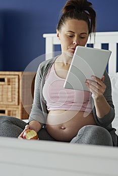 Vertical image of woman using tablet while sitting in bed photo