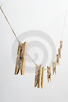 Vertical image of wooden laundry pegs and rope against white background