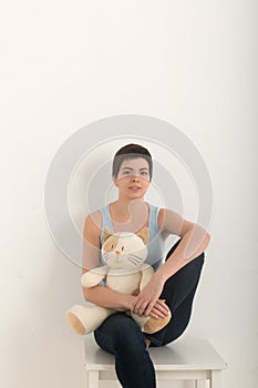 Vertical image of young girl looking at camera, portrait of a beautiful brunette woman with a lovely plush toy cat in