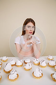 Vertical image of young woman by the table with cakes