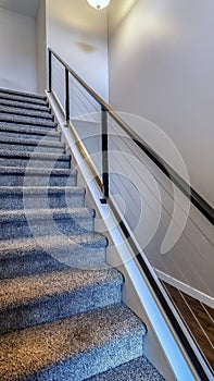 Vertical Indoor stairs of home with metal handrail and gray carpet on the treads