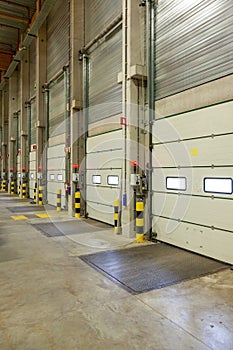 Vertical interior shot of a warehouse with a row of doors and control panels next to it