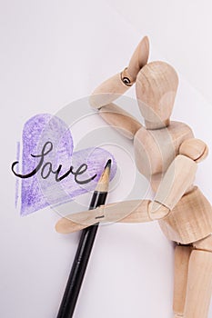 Vertical jointed wooden doll hand on head laying by sketched Purple Heart word love written inside