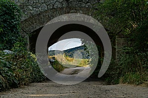 Vertikálna krajina tunela pod kamenným mostom s malebným výhľadom na kopce v pozadí
