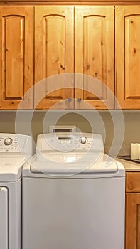 Vertical Laundry room interior with washer dryer and counter against the beige wall