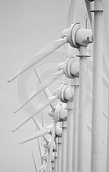 Vertical, low angle, greyscale shot of a line of white windmills from a side view