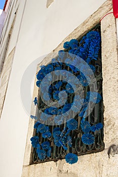 Vertical low angle shot of a blue paper flowers decorating a window