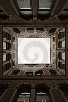 Vertical low angle shot of a building creating a suqare with white sky seen through it
