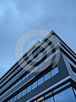 Vertical low angle shot of a glass modern building under a blue sky