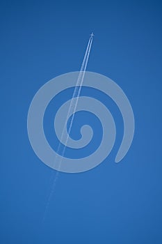 Vertical low angle shot of jet trails on the blue sky