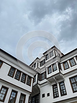 Vertical low angle shot of a modern white building with black windows under the cloudy sky