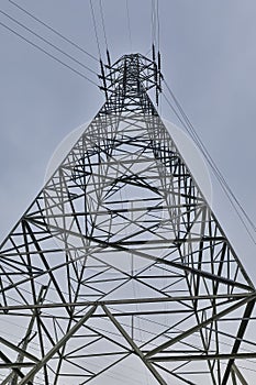 Vertical low angle shot of a power line tower  on a gloomy sky background