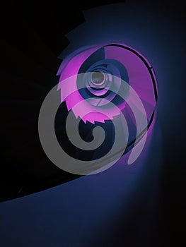 Vertical low angle shot of a tall spiraling staircase in aesthetic purple color