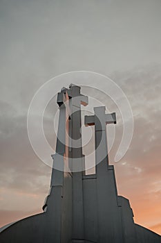 Vertical low angle shot of the Three Crosses in Vilnius, Lithuania under a colorful sunset sky