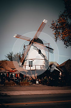 Vertical low angle shot of a windmill in a town with the grey sky in the background