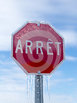 Vertical low angle view of French stop sign encased in ice after ice storm