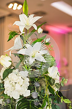 Vertical luxurious floral arrangement composition in white tones of lilies, roses, hydrangeas.