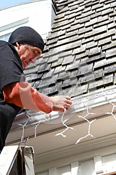 Vertical man on ladder hanging Christmas lights