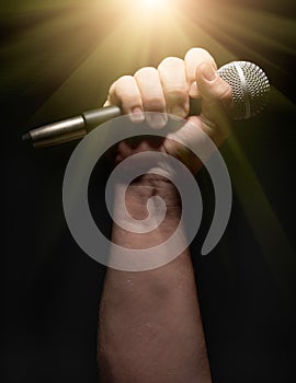 Vertical Microphone Clinched Firmly in Male Fist on a Black Background photo
