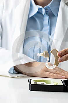 Vertical midsection of caucasian female doctor holding hearing aid