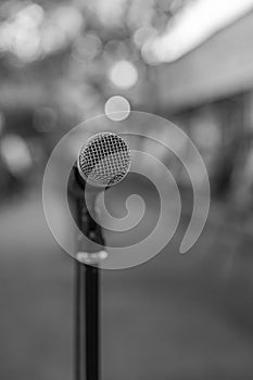 Vertical monochrome shot of the microphone on the stand with a bokeh background
