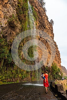 Vertical of a mother with son at the Anjos waterfall that falls on the road in Madeira, Portugal.