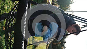 Vertical of Mother tries to put son on swing nest in cottage house yard