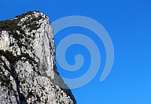 Vertical mountain cliff against clear blue sky