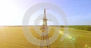 Vertical movement flight near high voltage electricity tower and power lines at green and yellow field