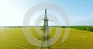 Vertical movement flight near high voltage electricity tower and power lines at green and yellow field