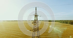 Vertical movement flight near high voltage electricity tower and power lines at green and yellow field