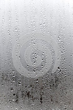 Vertical natural background, condensation on glass with drops flowing down, humidity and foggy blank. Outside , bad weather, rain