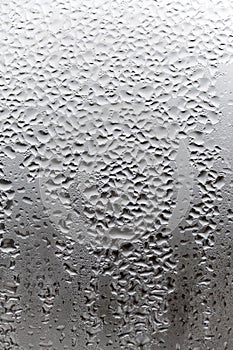 Vertical natural background, condensation on glass with drops flowing down, humidity and foggy blank. Outside , bad weather, rain