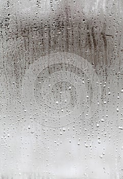 Vertical natural background, condensation on glass with drops flowing down, humidity and foggy blank. Outside , bad weather, rain