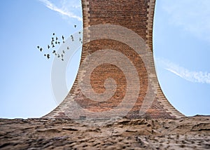 Vertical old railway arch viaduct bridge made of stone and brick looking up ground high above in the blue sky birds taking off