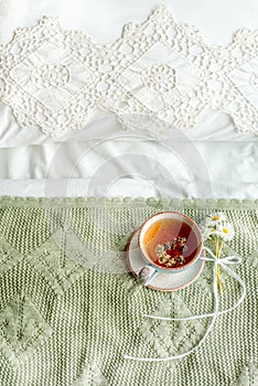 Vertical, olive plaid,cup of natural herbal tea from mint and lemon balm in bed,morning close up. Cozy atmosphere.Openwork lace,