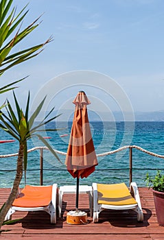 Vertical of an orange beach umbrella and lounge chairs in a  relaxing environment by the sea