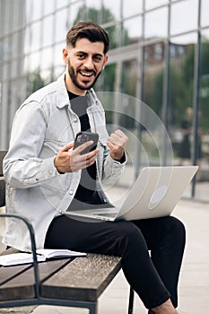 Vertical orientation of happy business man enjoy success on mobile phone. Joyful guy reading good news on smartphone