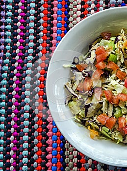 Vertical overhead shot of red cabbage, tomato, carrot, and celery salad bowl