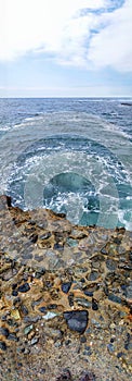 Vertical panorama of a rocky ledge dropping off into the ocean.