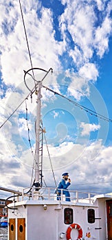 Vertical panorama with sailor figure on a fishing boat and blue sky with clouds