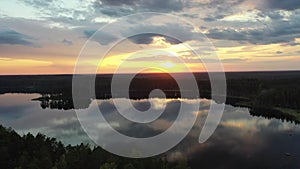 A vertical panorama (tilt) of a forest, lake and a beautiful sunset sky.