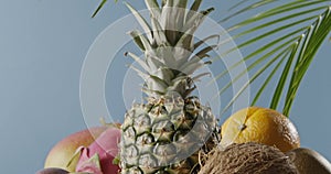 Vertical panoramic upward slow motion with composition from fresh natural exotic fruits on a wooden table on a blue