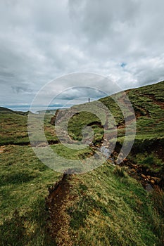 Vertical of a person standing on a hill on Skie island in Scotland captured under a grey cloudy sky