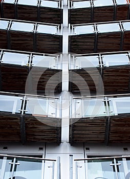 Vertical perspective view of angled modern glass apartment balconies on a blue steel building