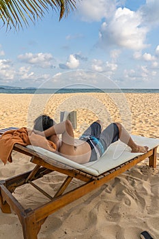 Vertical photo of Asian man sunbathing and reading book