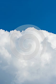 Vertical photo of beautiful dense white clouds at the bottom of the frame. Blue sky at the top of the frame