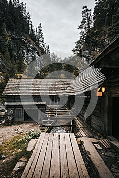Vertikální fotografie krásné dřevěné chaty hluboko v lese - Mlyny Oblazy Slovensko. Starý dřevěný mlýn s kameny na pozadí