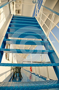 Vertical photo of a blue staircase on the deck of a cruise ship. Summer sunny day travel concept